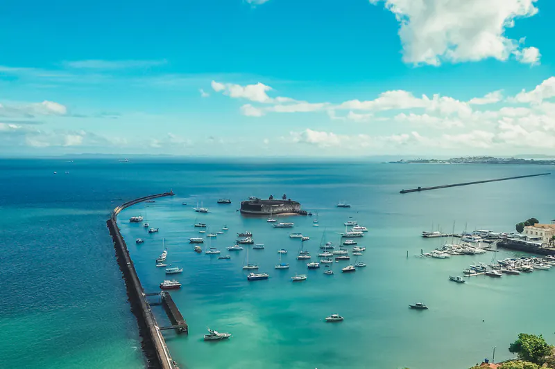 O Forte São Marcelo no mar, com barcos ao lado, em Salvador.